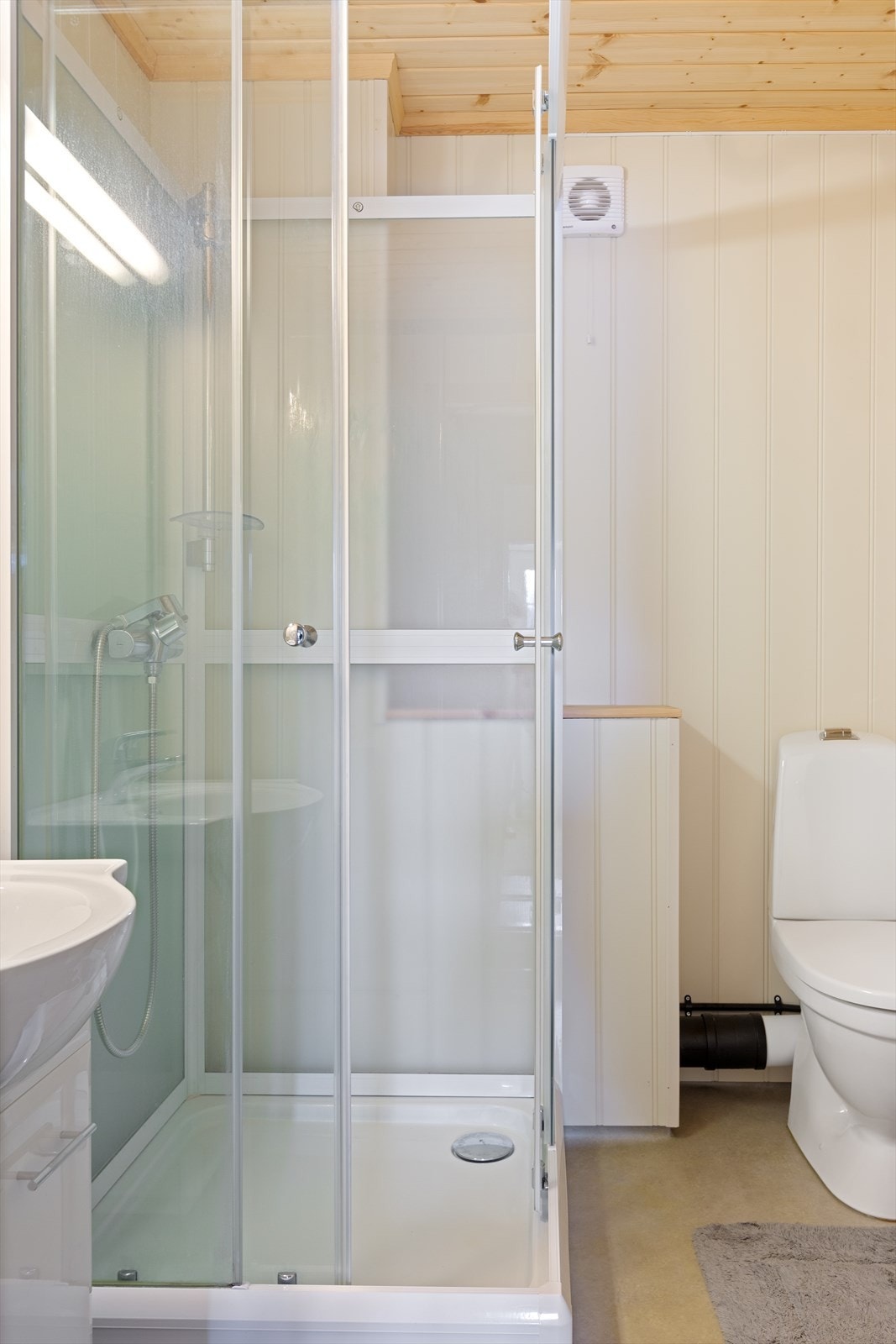 Bad i underetasjen, med malte mdf-plater og gulvbelegg. Servantinnredning, toalett og dusjkabinett. Galleribilde