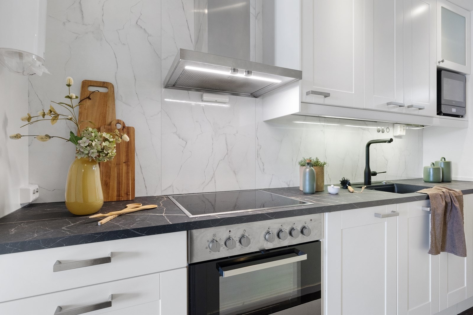 Stilrent kjøkken i lys utførelse, med hvite fronter og laminat benkeplate. Galleribilde