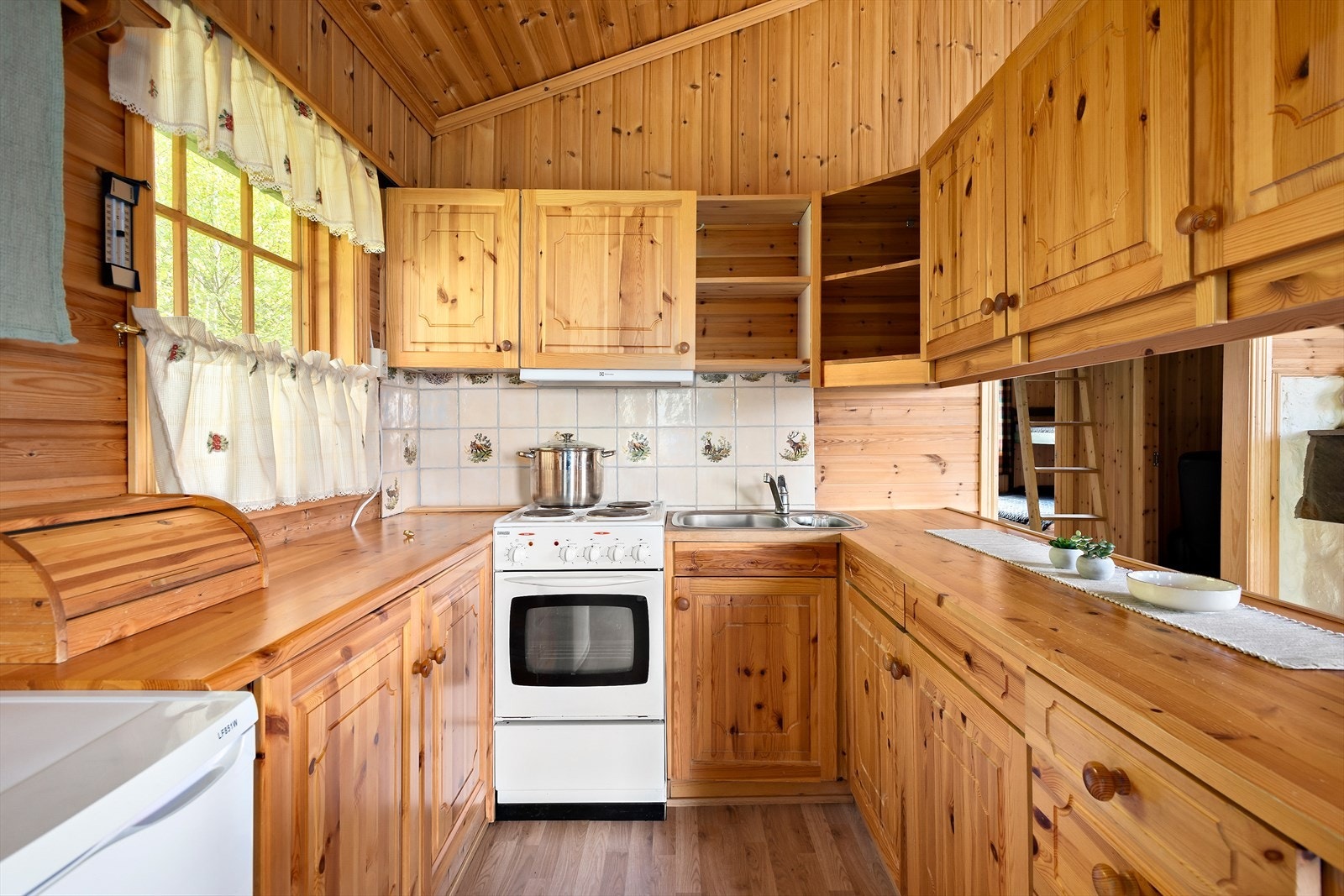 Kjøkkeninnredning av laminerte skrog med heltre fronter, Heltre benkeplate med nedfelt oppvaskkum i stål med ett-greps blandebatteri. Kjøkkenet er utstyrt med hvitevarer som kjøleskap
og komfyr med koketopp. Galleribilde