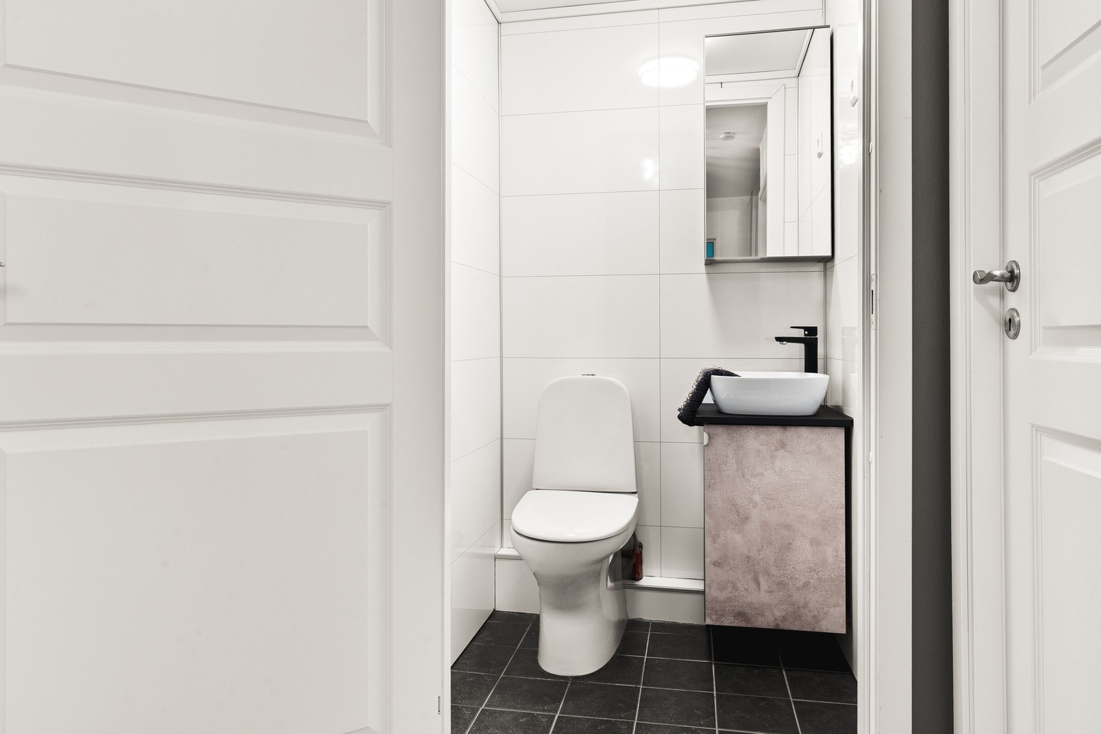 Toalettrommet har fliser på gulv og er innredet med toalett og baderomsinnredning med servant. Galleribilde