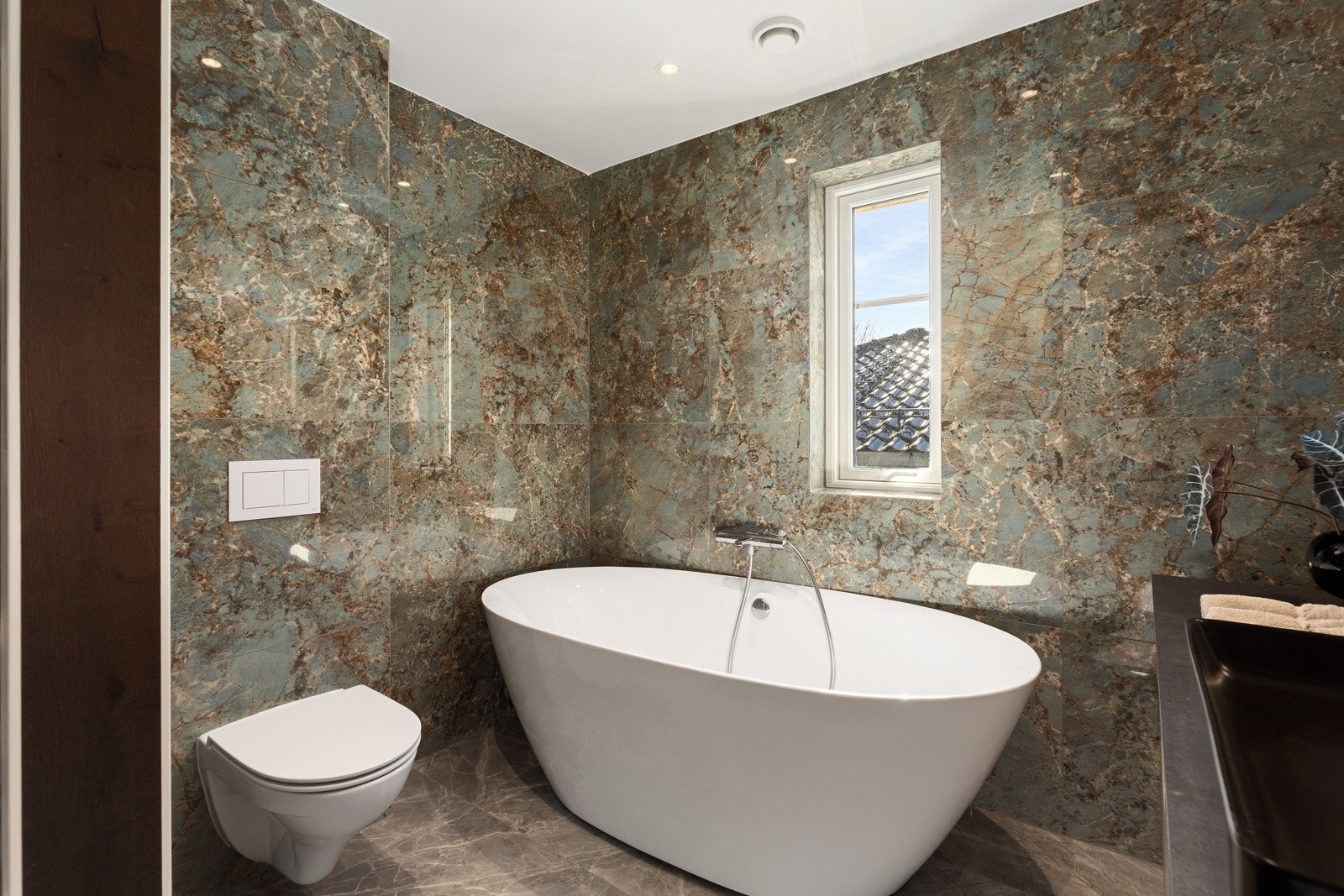 Videre er det et frittstående badekar og veggfestet toalett. Galleribilde