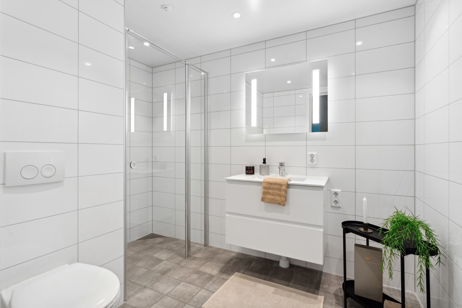 Moderne flislagt bad med vannbåren varme, dusjhjørne med glassvegger og stilfull servantinnredning. Komfort og funksjonalitet på sitt beste. Galleribilde