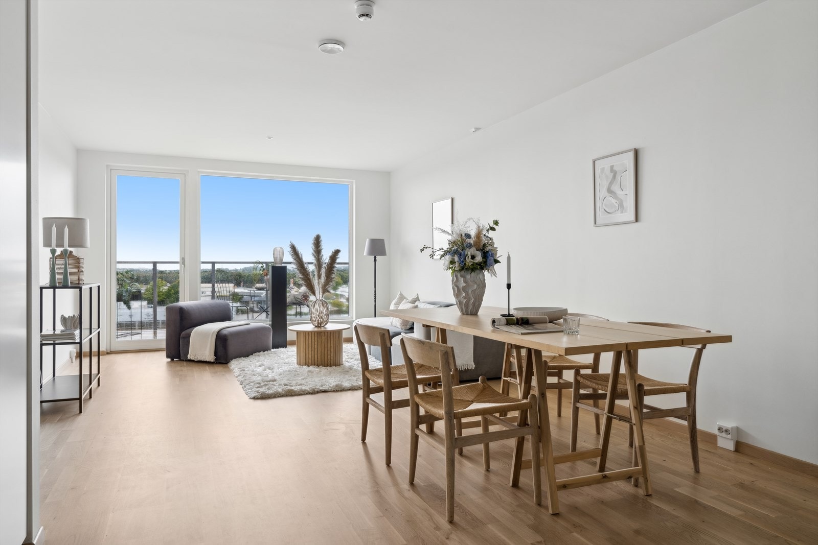 Lys og romslig stue med store vinduer som slipper inn naturlig lys, og en åpen planløsning som gir en luftig og innbydende atmosfære. Galleribilde