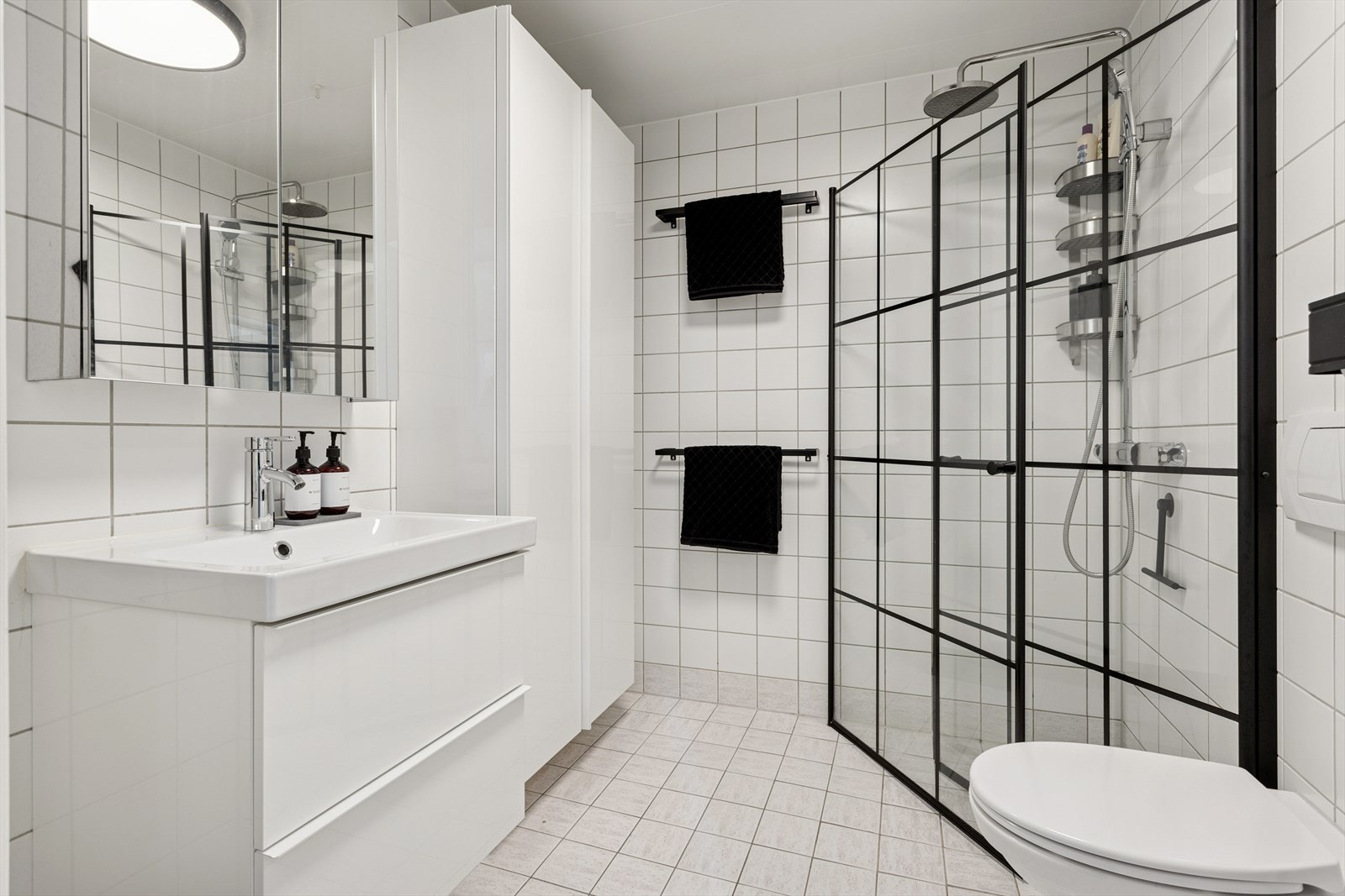 Flislagt baderom i tidløst uttrykk. Oppgradert i 2021 med nye dusjdører og ett høyskap. Galleribilde