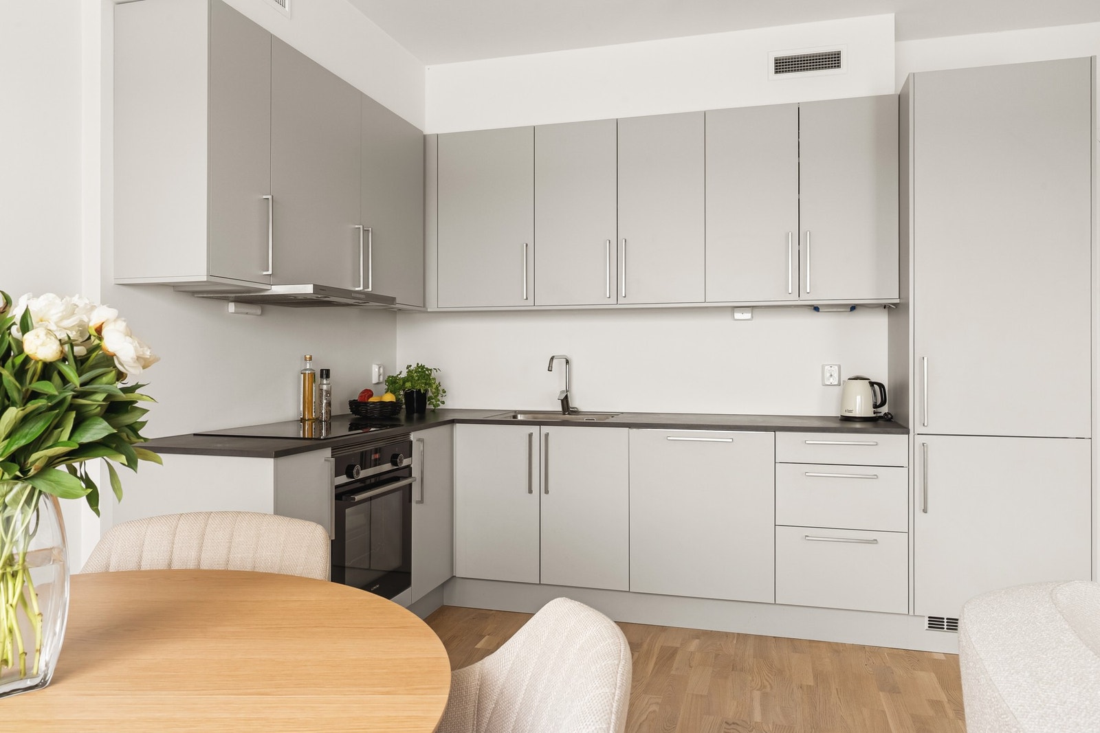 Lekker kjøkkeninnredning fra Sigdal med grå, glatte fronter med benkeplate av laminat. Kjøkkenvask i stål nedfelt i benken. Galleribilde