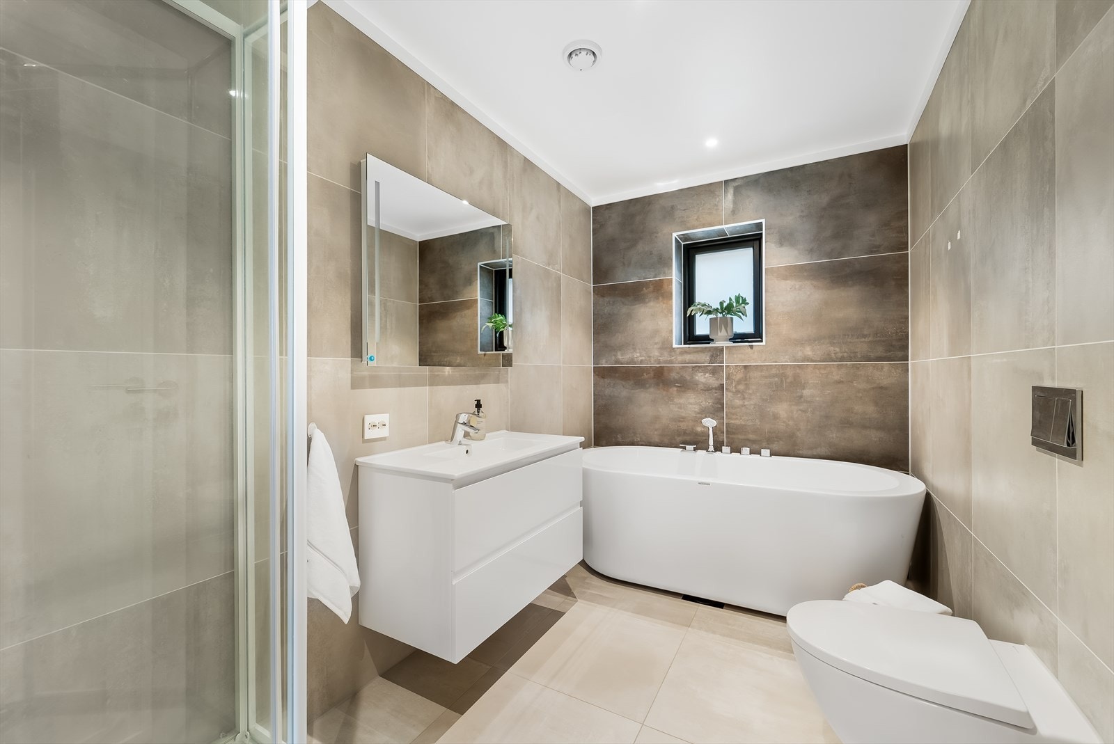 Badet i 1. etasje er innredet med lys innredning, speil med innfelt lys, dusjkabinett, badekar og vegghengt toalett. Galleribilde