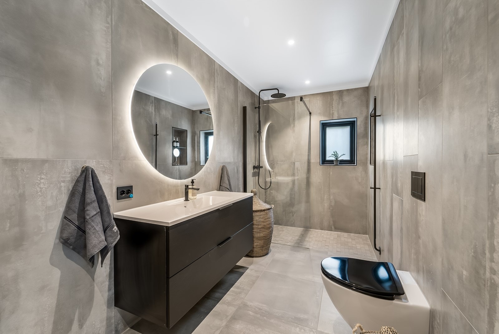 Badet i 2. etasje har mørk innredning med svarte detaljer. Badet er innredet med baderomsinnredning, vegghengt toalett og dusjnisje med glassvegg. Galleribilde