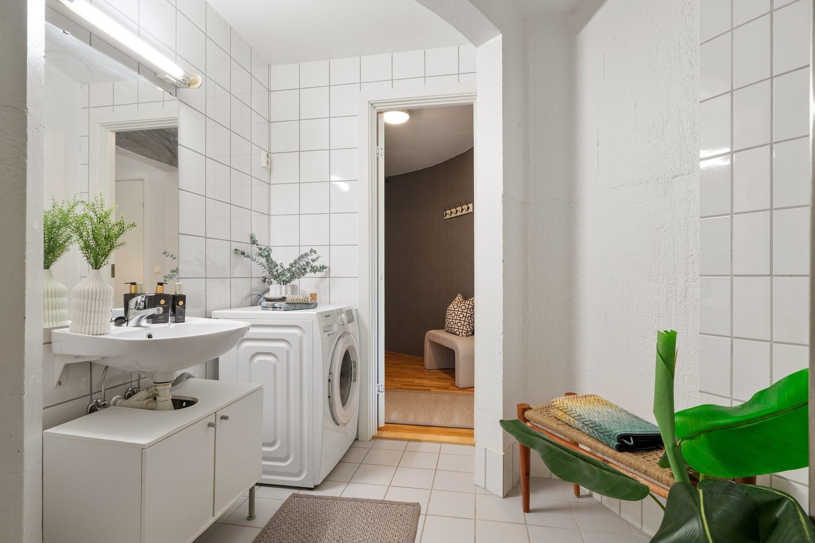 Badet er utstyrt med servant med speil og belysning, dusjnisje med glassbyggerstein og dusjforheng, gulvstående toalett samt opplegg for vaskemaskin. Galleribilde