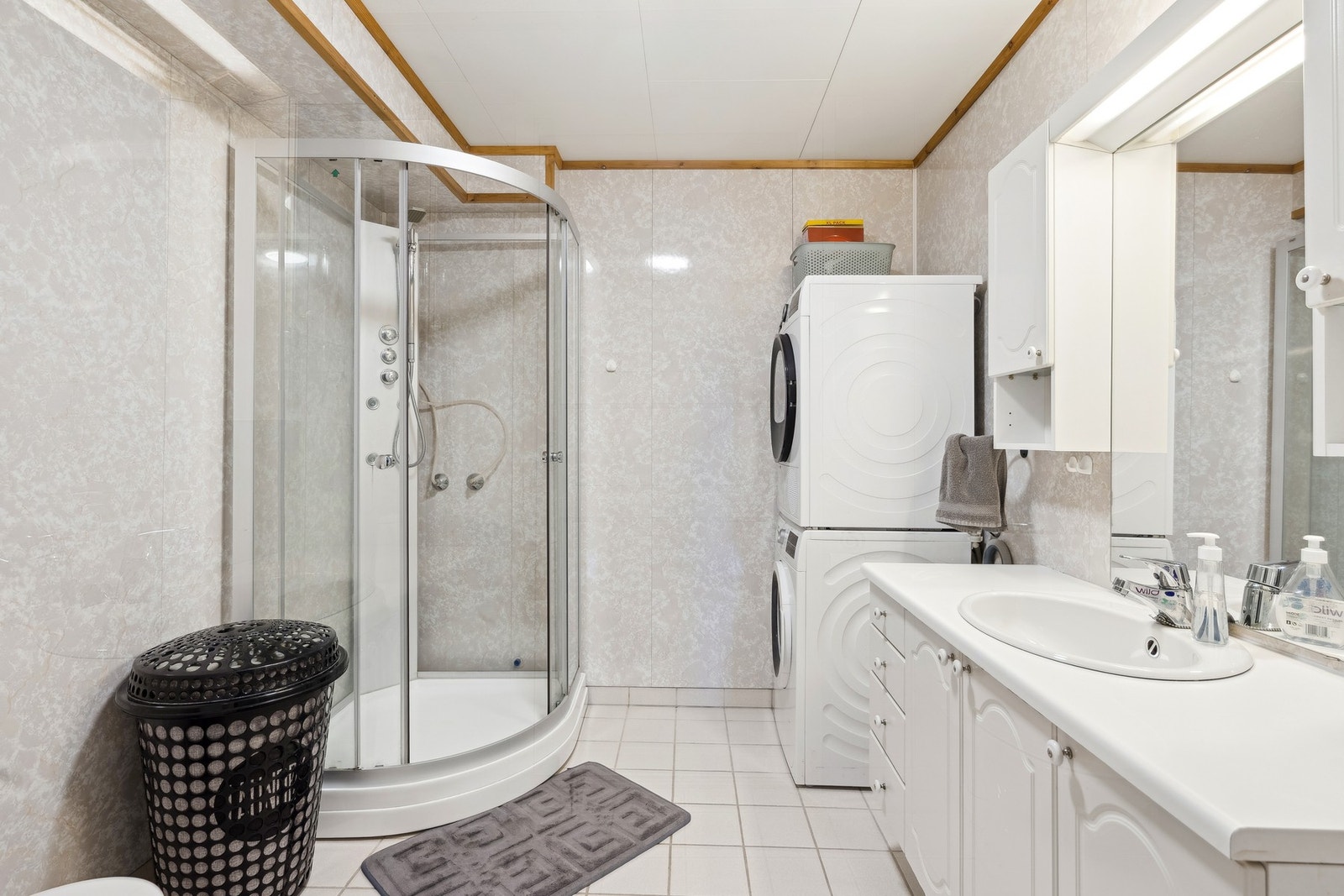 Badet har praktisk innredning med nedfelt servant, toalett, dusjkabinett og opplegg for vaskemaskin Galleribilde