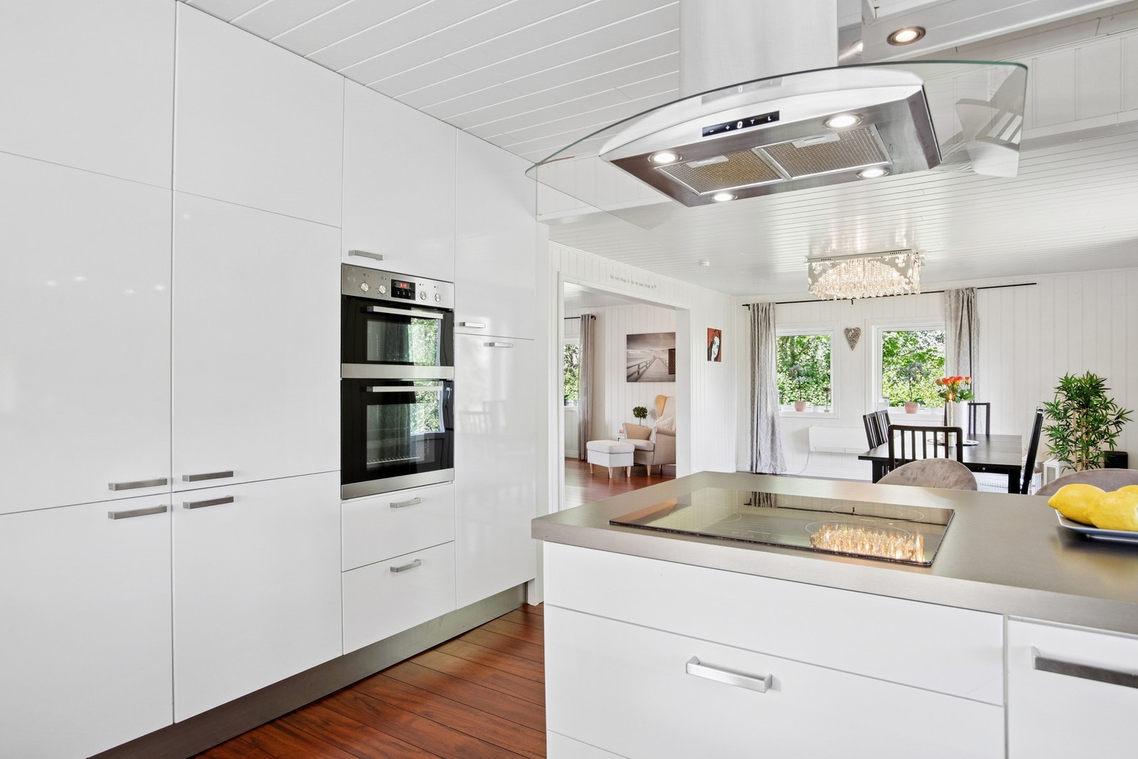 Kjøkkenet er utstyrt med integrerte hvitevarer, dobbel stekeovn og moderne ventilator - alt i en sømløs, hvit innredning. Galleribilde