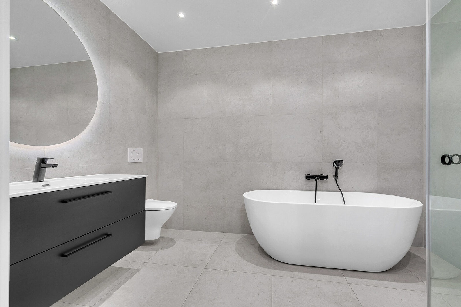 Romslig bad med fliser, varmekabler, dusjnisje og badekar Galleribilde