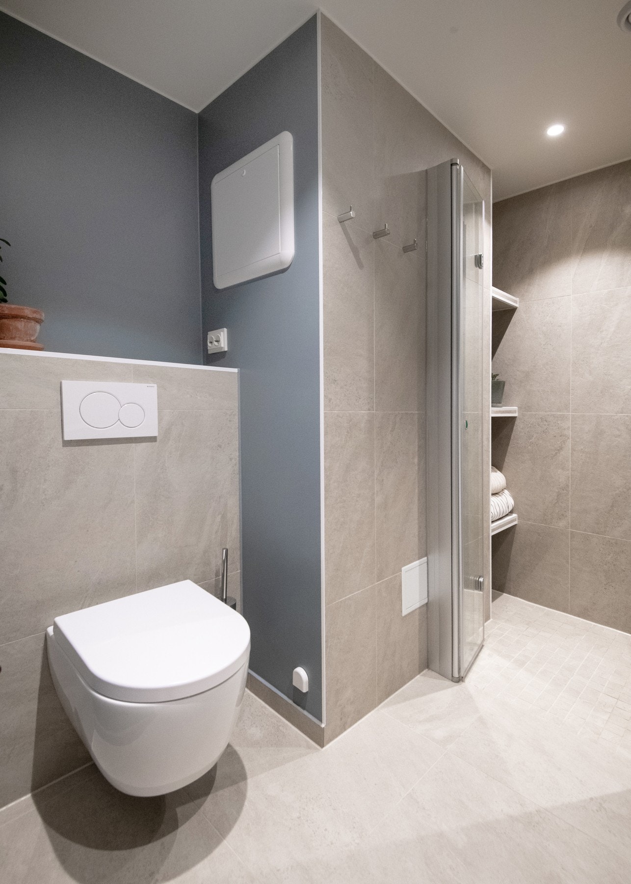 I dusjsonen finner du både flislagte hyller som gir praktisk oppbevaringsplass for håndklær og annet tilbehør, samt et elegant innhuk for oppbevaring av dusjsåper. Galleribilde