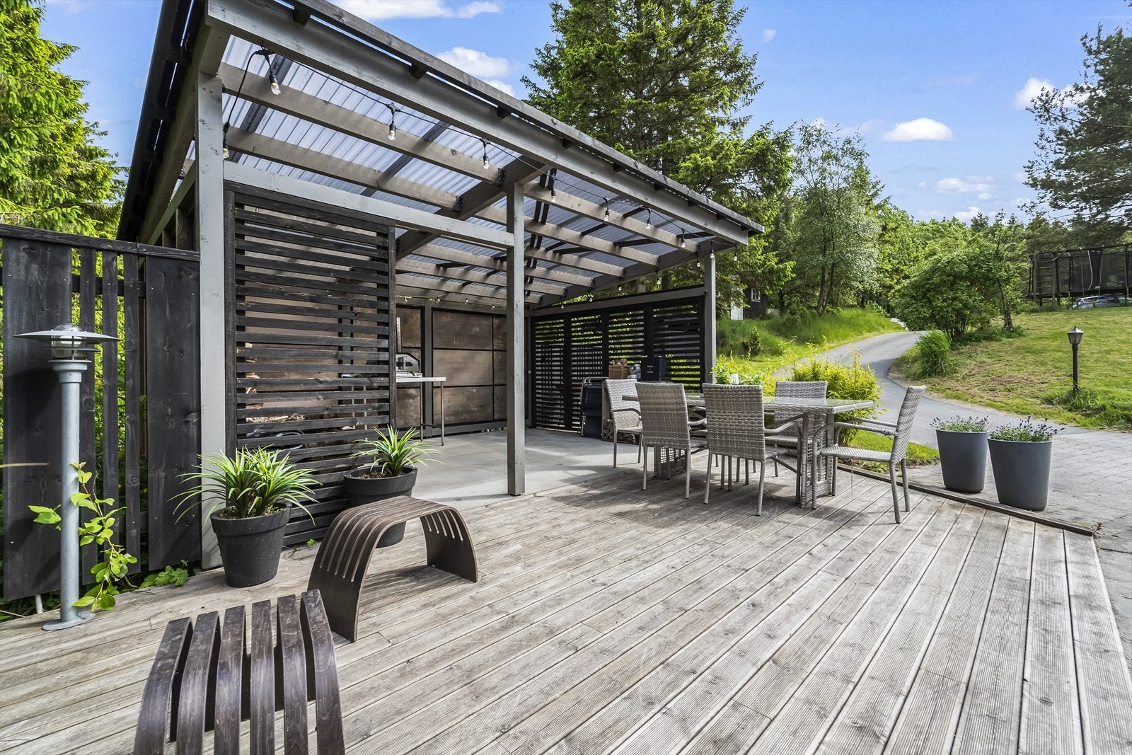 Trivelig uteplass med overbygd grillområde og spisegruppe - omgitt av frodig hage og grønne omgivelser, perfekt for lange sommerkvelder. Galleribilde