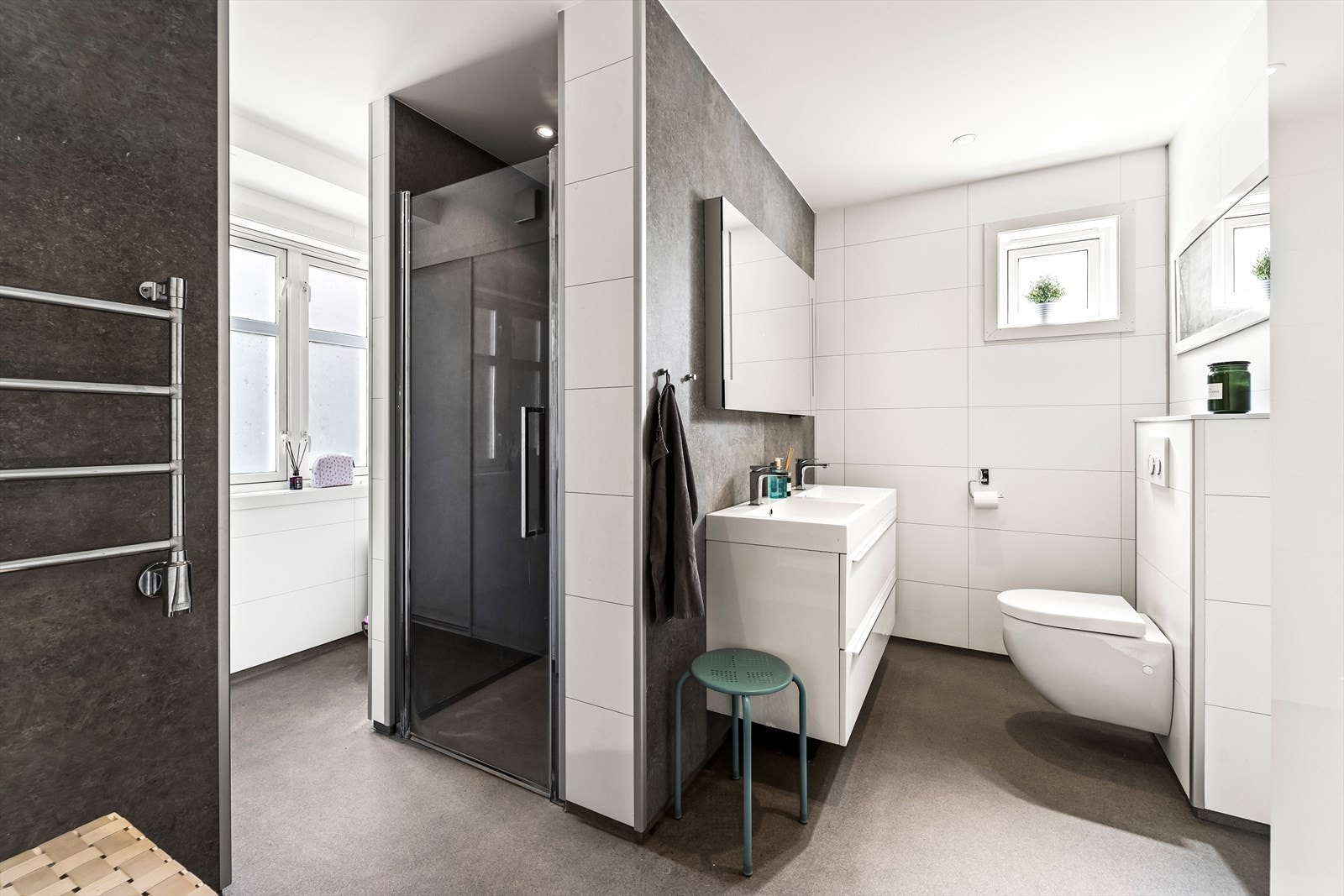 Stilrent bad med dusjløsning, vegghengt toalett og baderomsinnredning med speil. Galleribilde