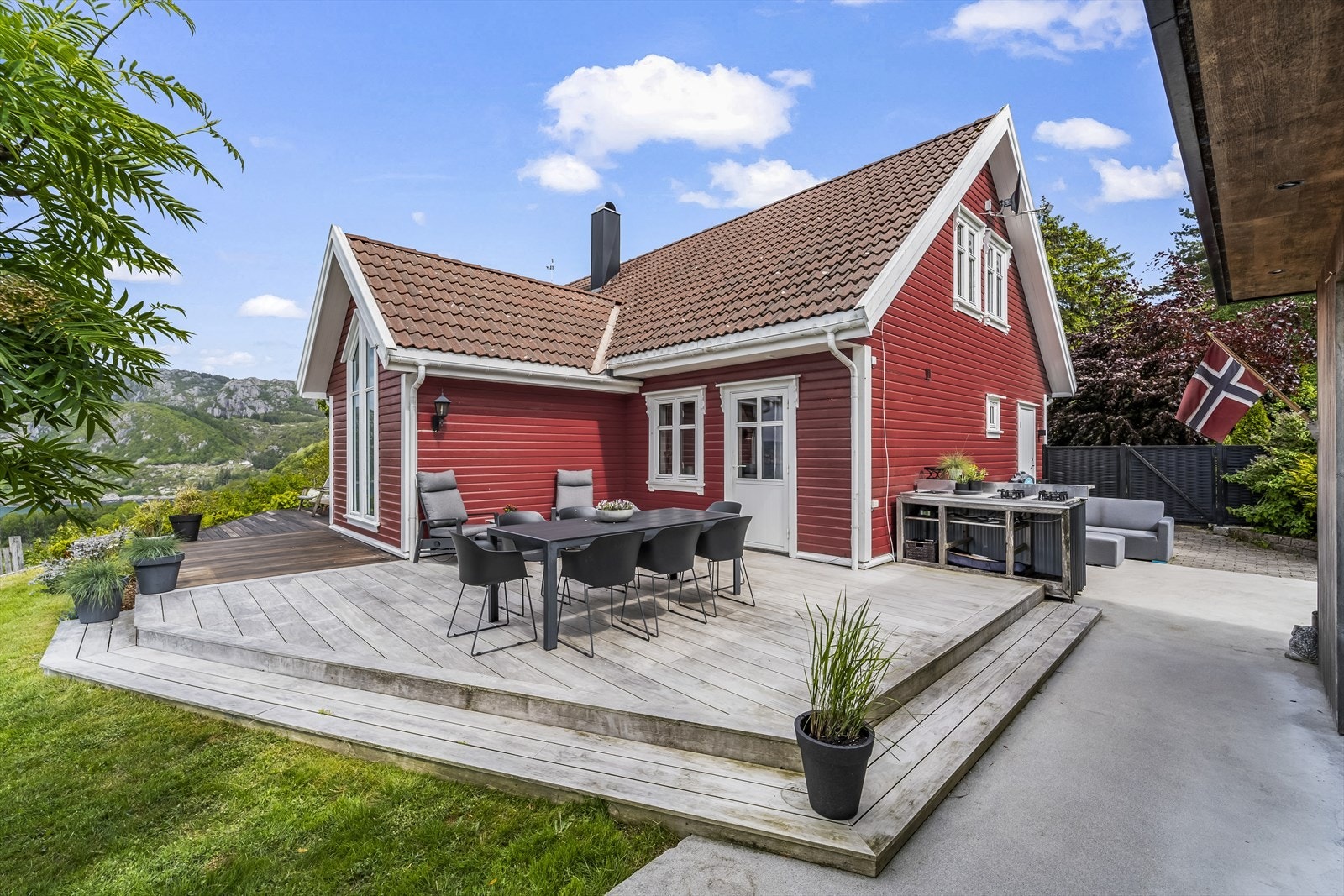 Stor og solrik terrasse rundt boligen med spisegruppe og loungemøbler. Galleribilde