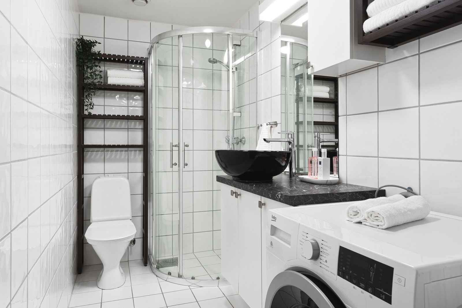 Badet er innredet med skap med overliggende servant, toalett, dusjhjørne og opplegg for vaskemaskin. Galleribilde