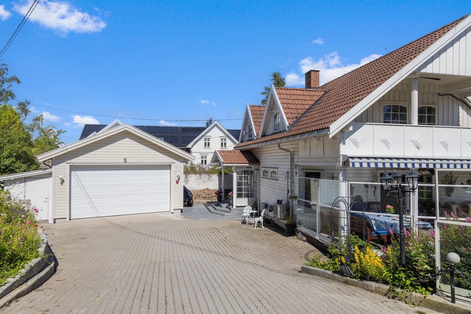 Stor stenbelagt gårdsplass og dobbelgarasje. Galleribilde