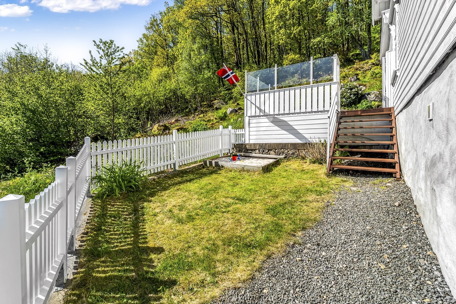 Tomta er pent inngjerdet med hvitt stakitt gjerde og har plenlagte områder. Galleribilde