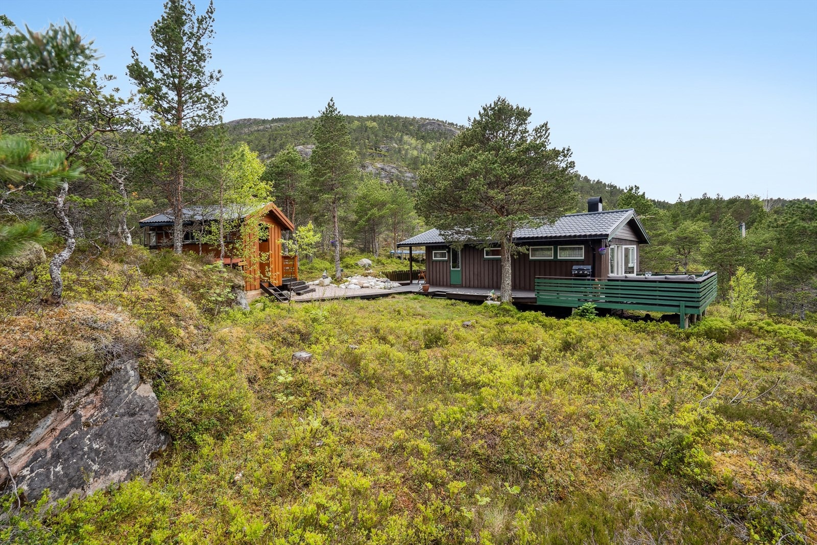 Tomten ligger fint til høyt oppe i terrenget med utsikt over fjord og sjø, og inneholder hytte med terrasser, og bod med lagringsplass. Galleribilde