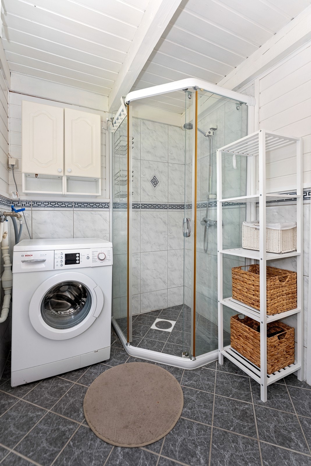 Badet er innredet med dusnisje og opplegg for vaskemaskin Galleribilde