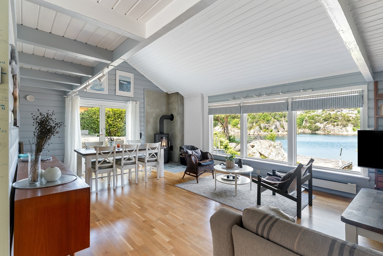 Stuen ligger i hjertet av hytten med store vindusflater mot hagen og sjøen - her kan du nyte i alle sesonger Galleribilde