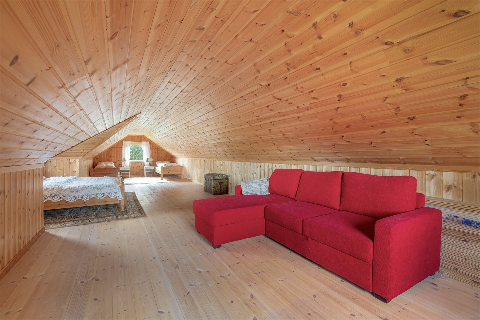 Loftet er innredet som et stort rom med furugulv og panel på vegg og tak. Galleribilde