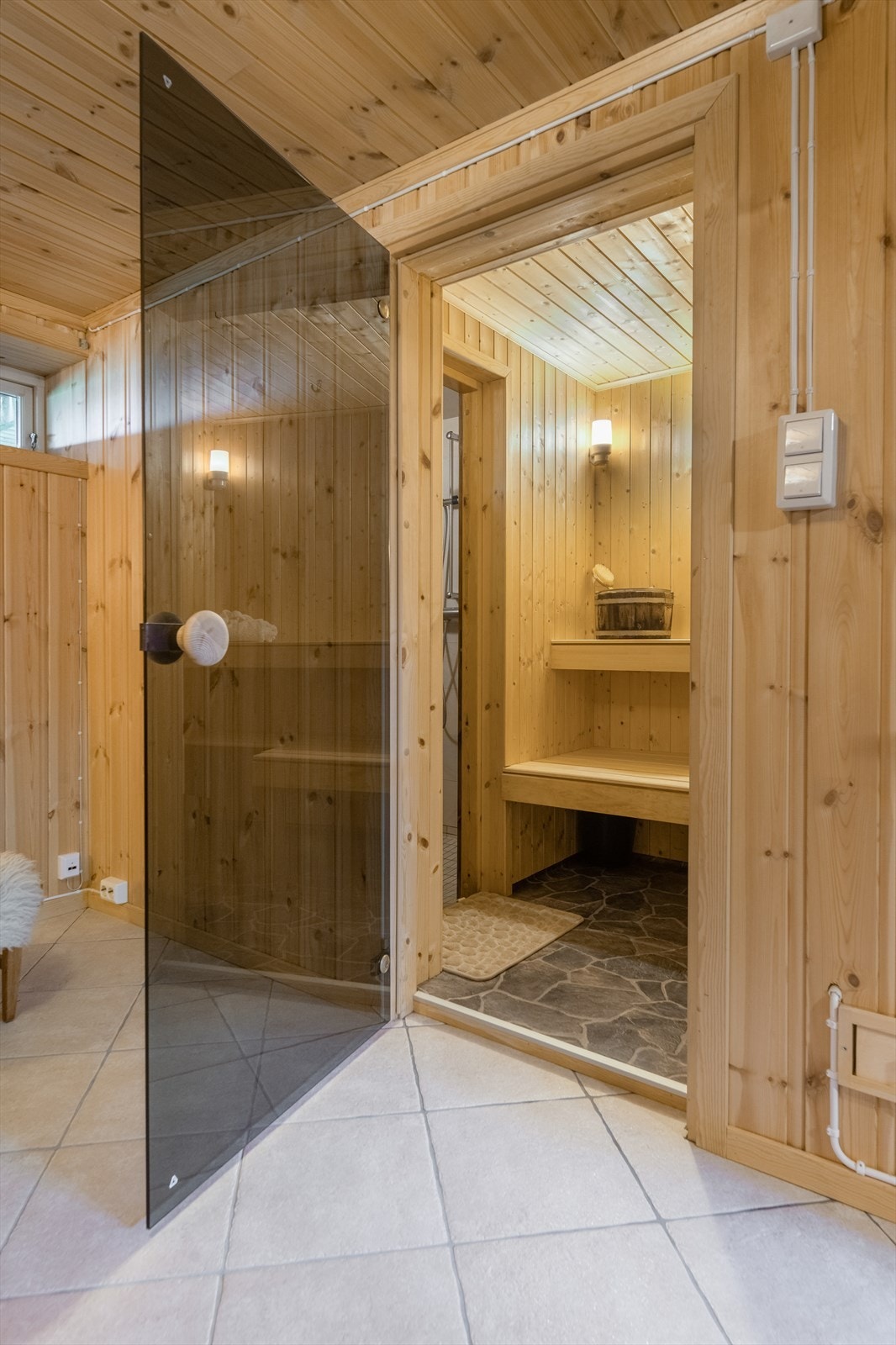 Fra kjellerstuen er det glassdør inn til badstuen, som er innredet med benker i to høyder og Hatvika badstueovn. Galleribilde