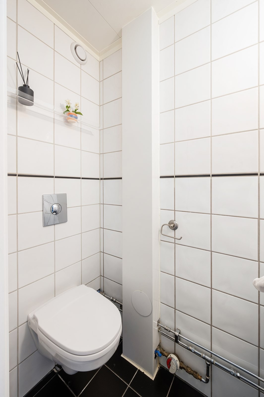 Enkel innredning med toalett, servant med underskap og speil. Galleribilde