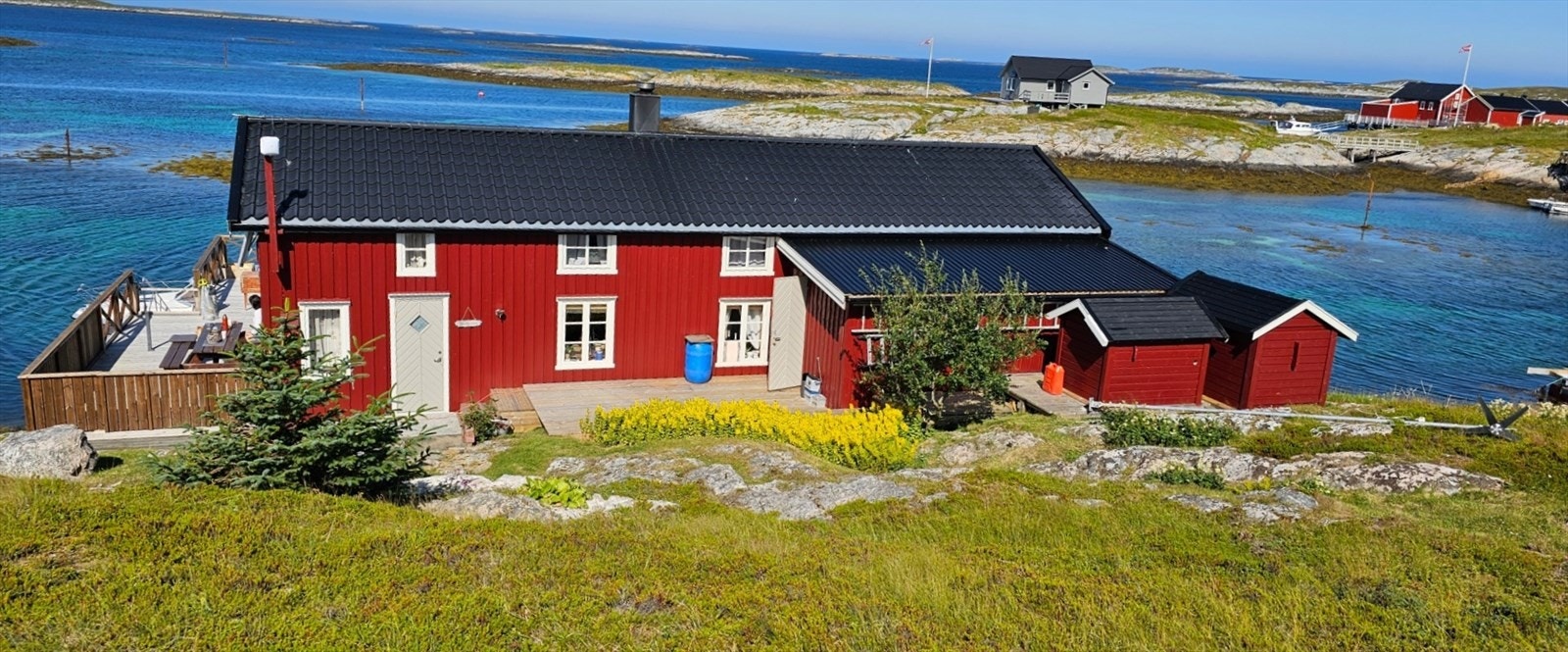 Selgers bilde. Her ser man de to uthusene som innehar vanntank og aggregat. Inngangsdøra til boden står åpen. Galleribilde