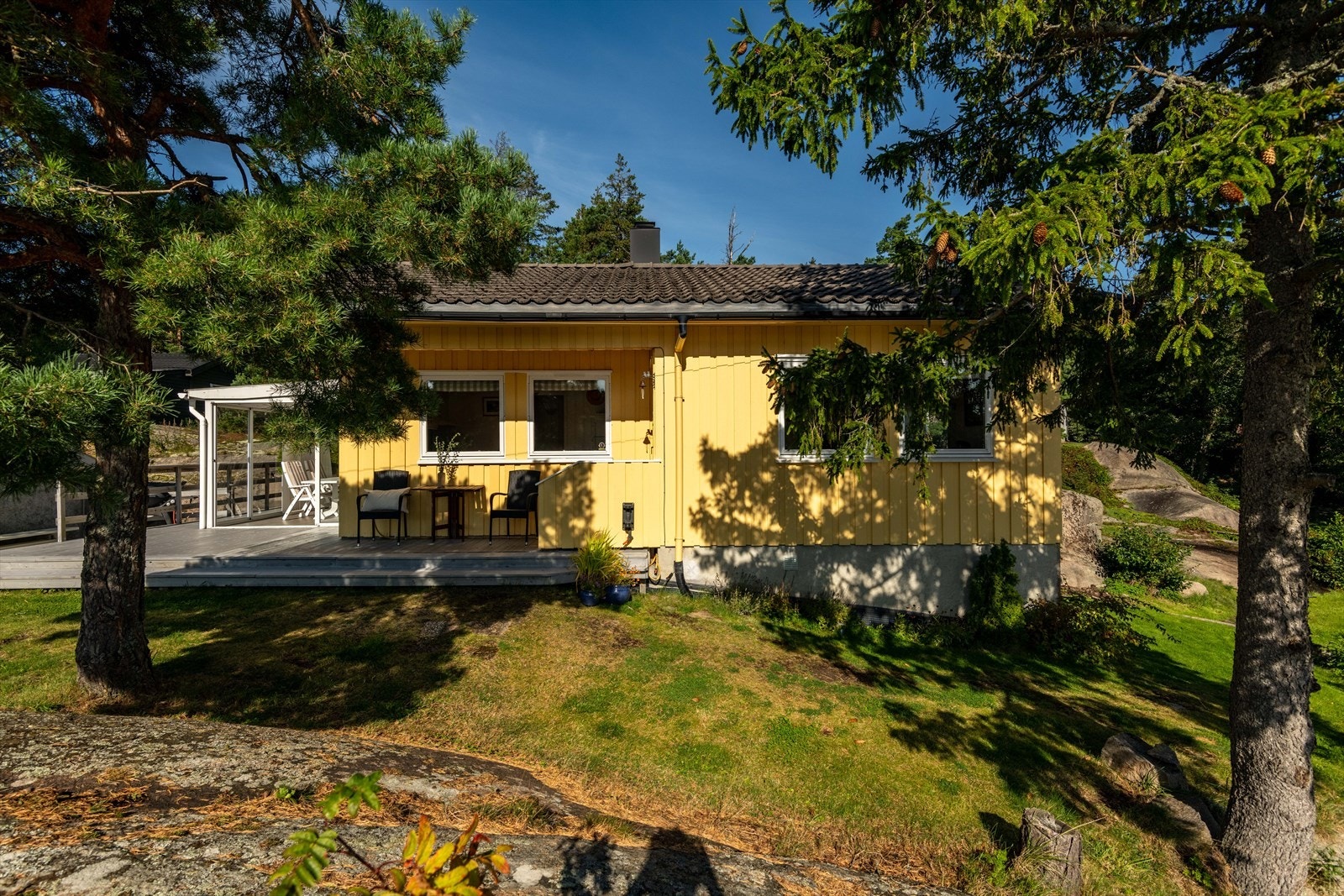 Skjærgårdslandskapets myke svaberg ligger i forgrunnen ut mot sjøen, og blanding av varmekjære løvtrær, kystfuru og granskog ligger i bakkant. Galleribilde