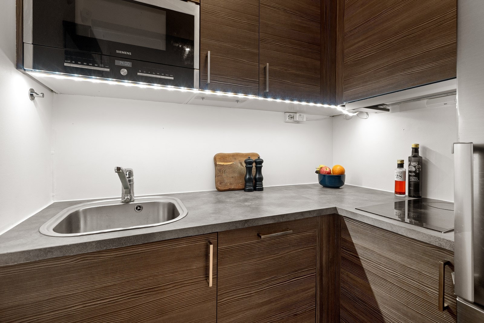 Kjøkken fra Sigdal med laminat benkeplate, integrert oppvaskmaskin og platetopp og nisje til kjøleskap. Galleribilde