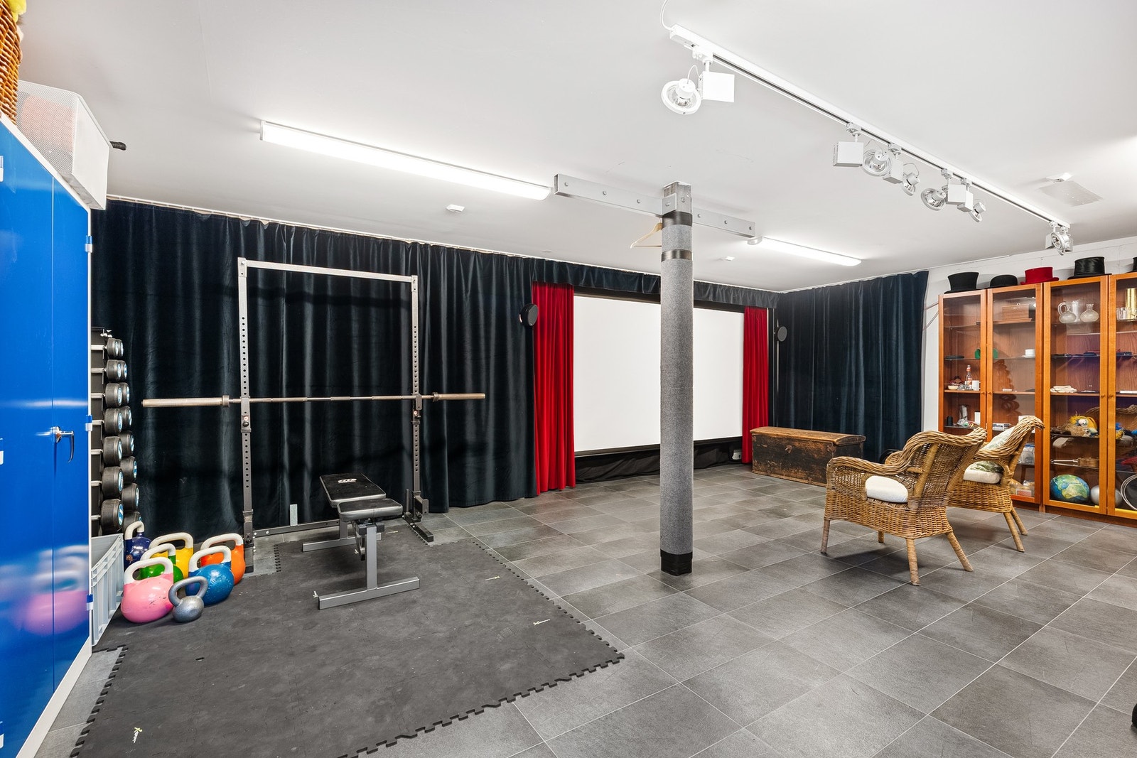 Multifunksjonelt rom med hjemmekino, treningsområde og smart lagringssystem bak gardiner Galleribilde