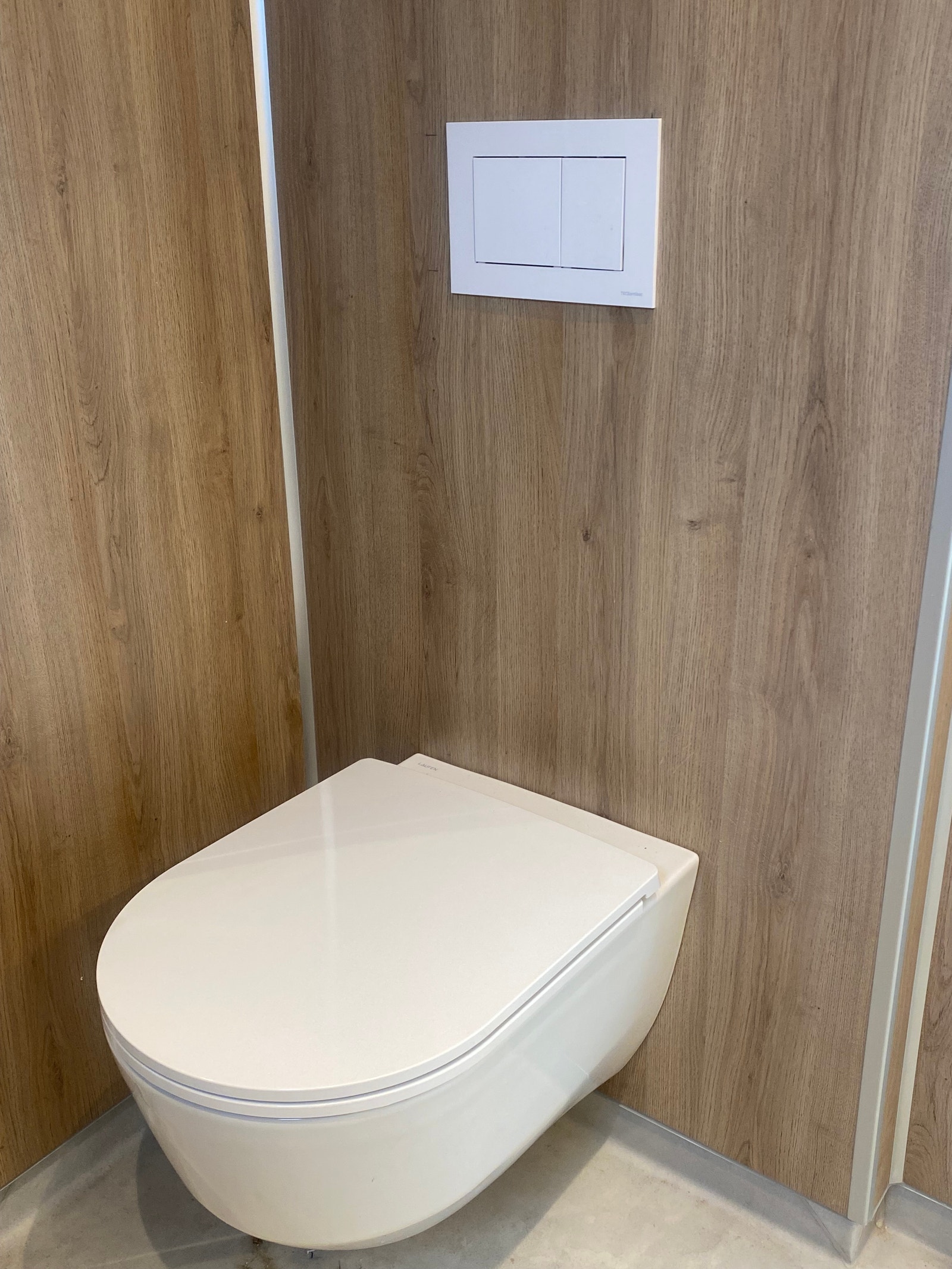 Lun og tidsriktig bad med eike plater på vegg.
Vegghengt toalett. Galleribilde