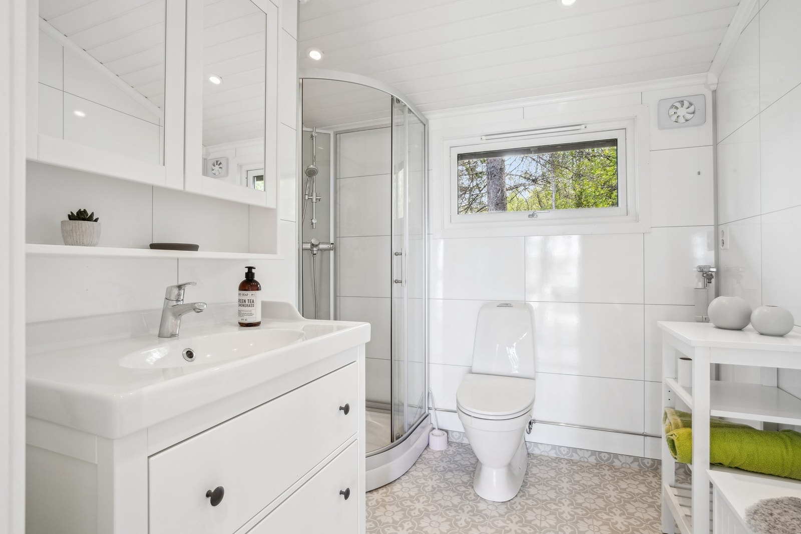 Lyst og moderne bad med innlagt varmekabler, dusjkabinett, gulvstående servantinnredning og speilskap med stikkontakt. Galleribilde