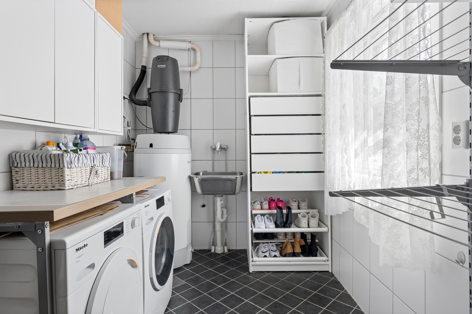 Praktisk vaskerom med opplegg for vaskemaskin, varmtvannsbereder, sentralstøvsuger og god oppbevaringsplass i overskap og hyller. Galleribilde