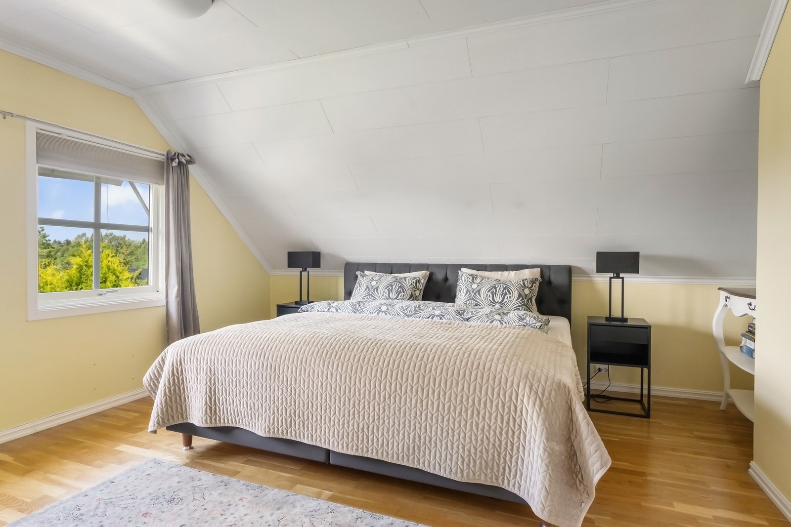 Lyst og romslig soverom med plass til dobbeltseng, nattbord og øvrig møblement. Galleribilde