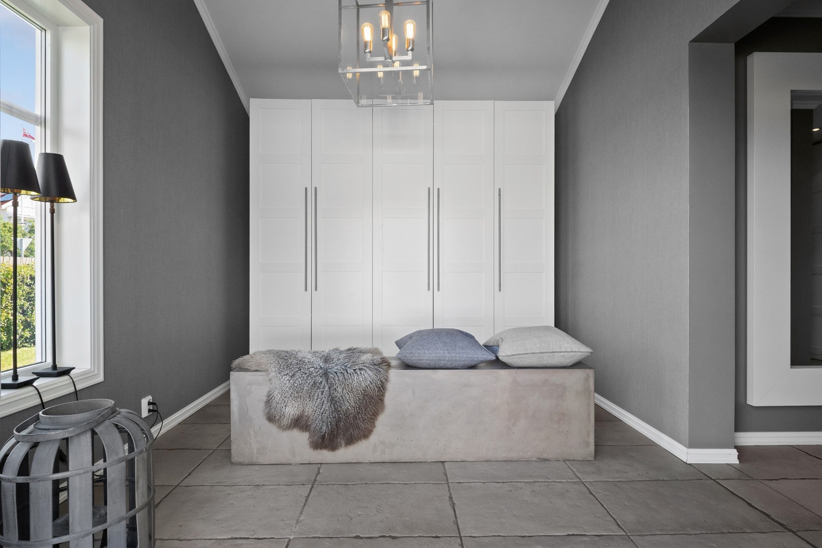 Yttertøyet ryddes enkelt bort i et stort garderobeskap med hvite fronter i profilert utførelse. Galleribilde