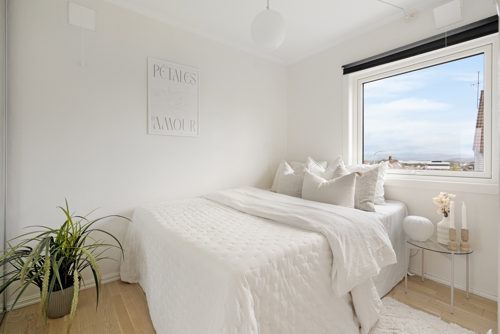 Leilighetens soverom fremstår lyst og luftig, med lyse farger på veggene og et stort vindu som gir flott innslipp av dagslys. Galleribilde