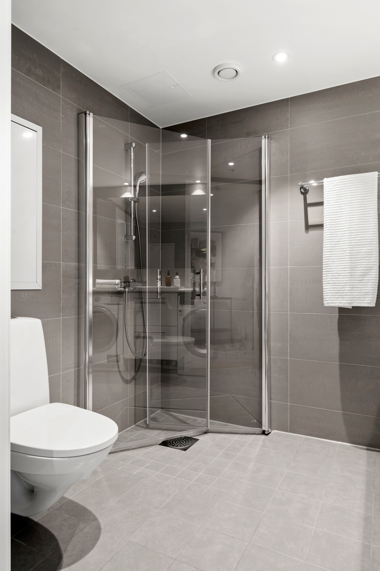 Badet er utstyr med dusjhjørne med innfellbare dører, servant med oppbevaring, vegghengt toalett og opplegg for vaskemaskin Galleribilde