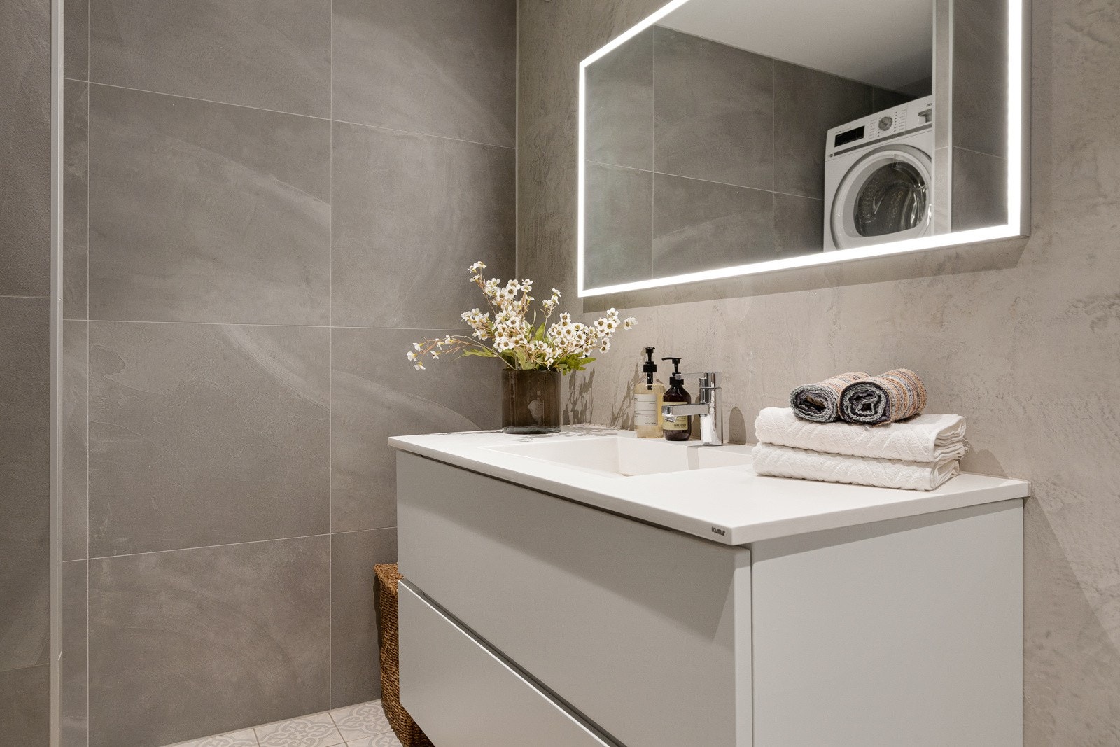 Innbydende og moderne baderom nyoppusset i 2018 med lyse, pene fliser og behagelige varmekabler i gulvet. Rommet er innredet med et servantskap med glatte fronter og heldekkende servant, samt speil med integrert belysning. Galleribilde