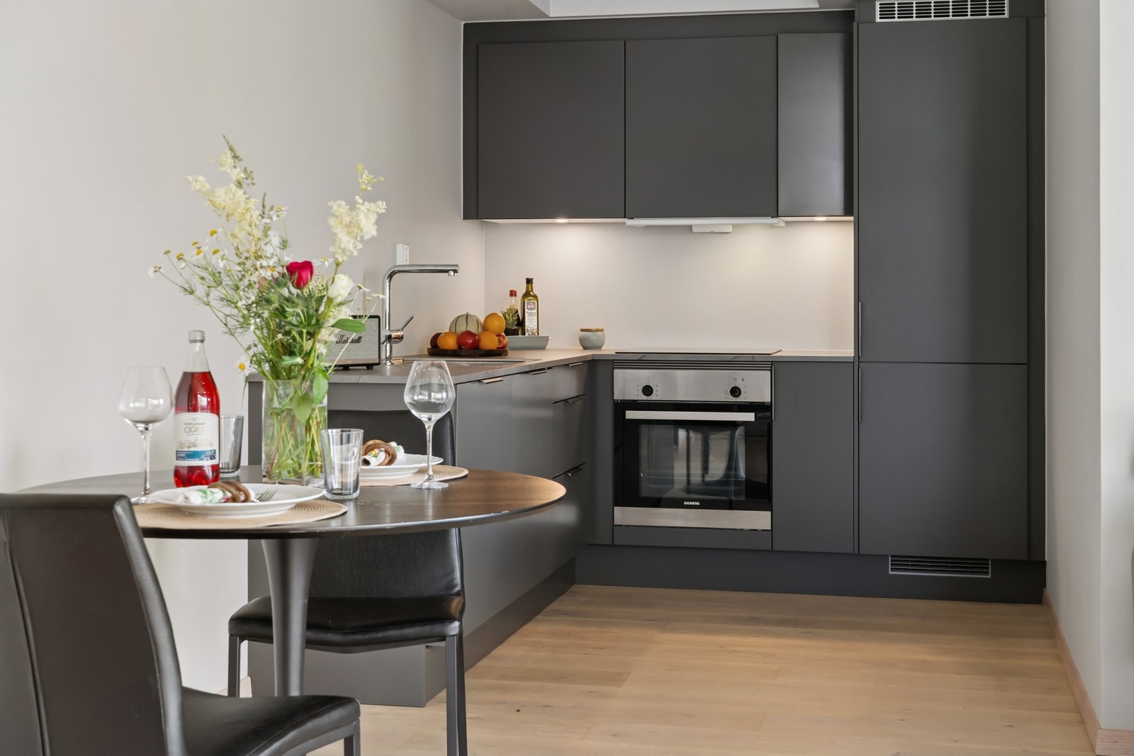 Laminert benkeplate i lysegrå marmorutførelse med nedfelt oppvaskkum i rustfritt stål. Det er montert belysning under overskap. Av utstyr medfølger integrert induksjonsplatetopp, komfyr, oppvaskmaskin, samt kombiskap kjøl/frys. Avtrekkshette over kokesone Galleribilde