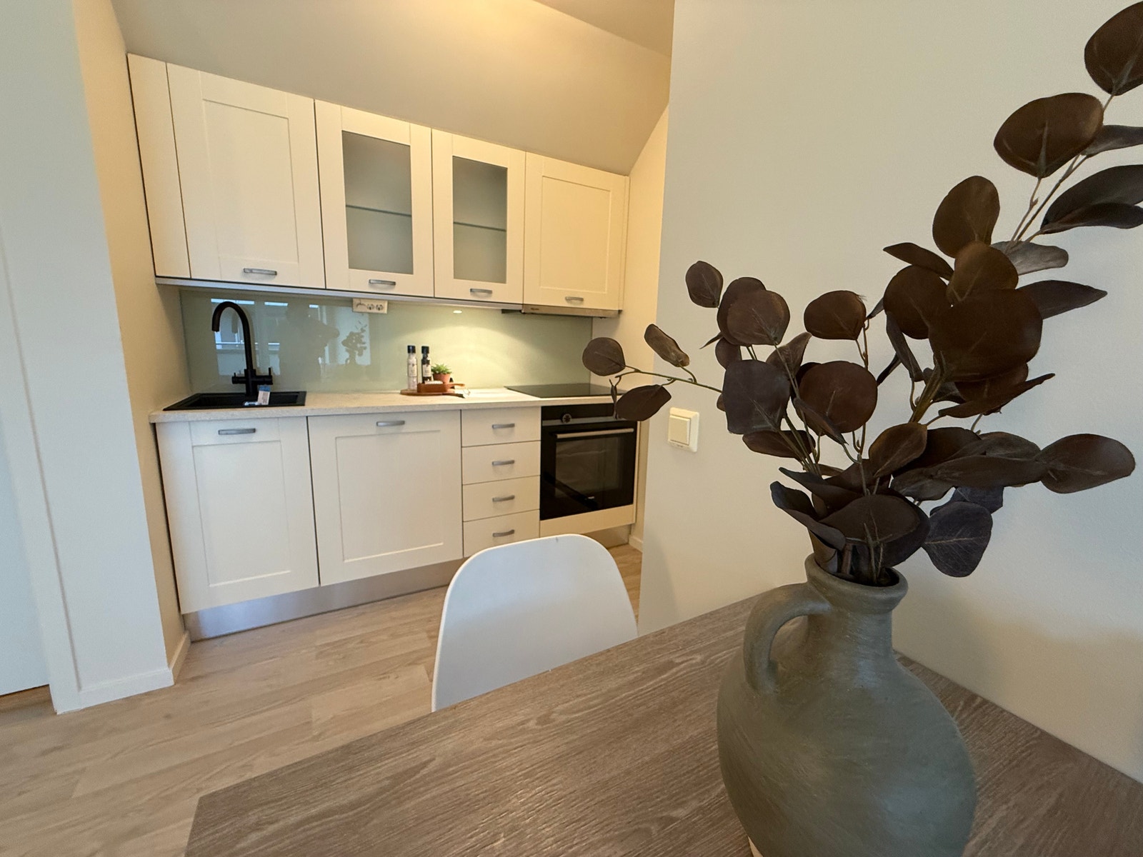 Bilde er fra leilighet 317 slik den fremstår nå Hyggelig spiseplass og kjøkken med integrerte hvitevarer. Platetopp, komfyr, vifte med avtrekk ut, oppvaskmaskin, kombiskap med kjøl og frys. Galleribilde