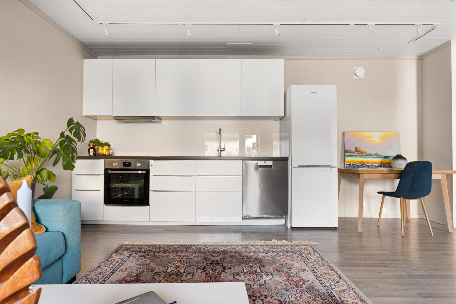 Kjøkkenet har slette fronter og en slitesterk laminert benkeplate med nedfelt platetopp og oppvaskkum i metall med ett-greps blandebatteri Galleribilde