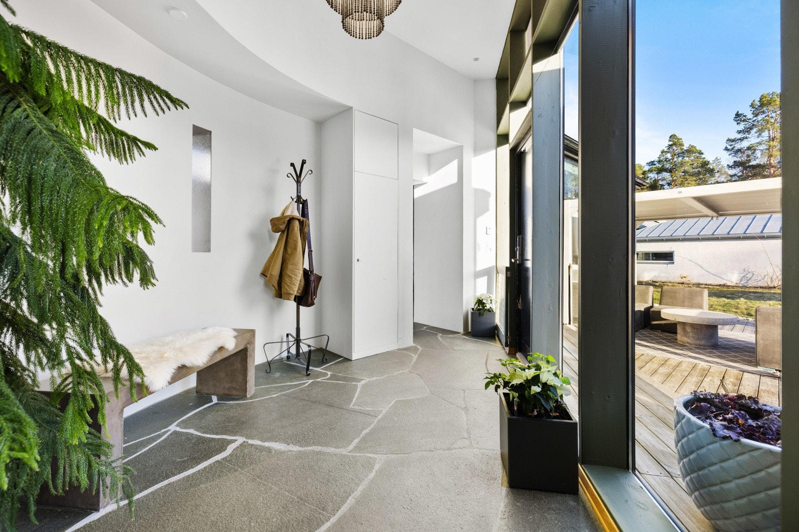 Det første som møter oss er en luftig gang med store skiferfliser og god plass til å henge av seg ytterklær og sette fra seg sko Galleribilde