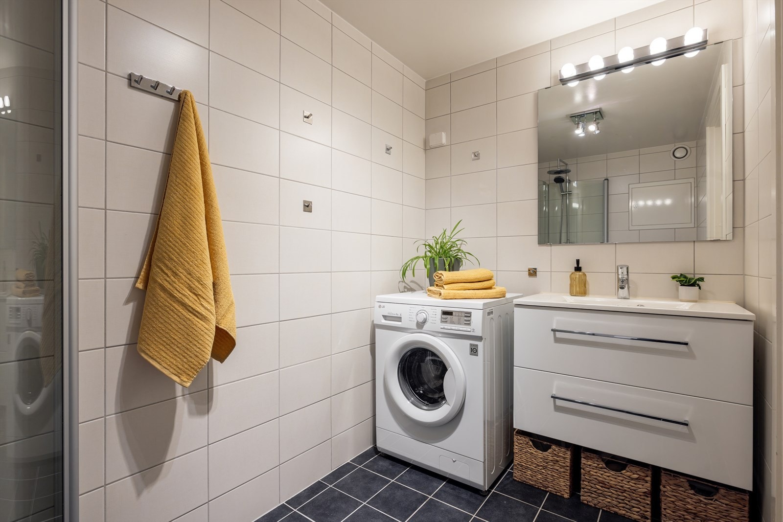 Lyst flislagt bad med elektrisk gulvvarme og opplegg for vaskemaskin Galleribilde