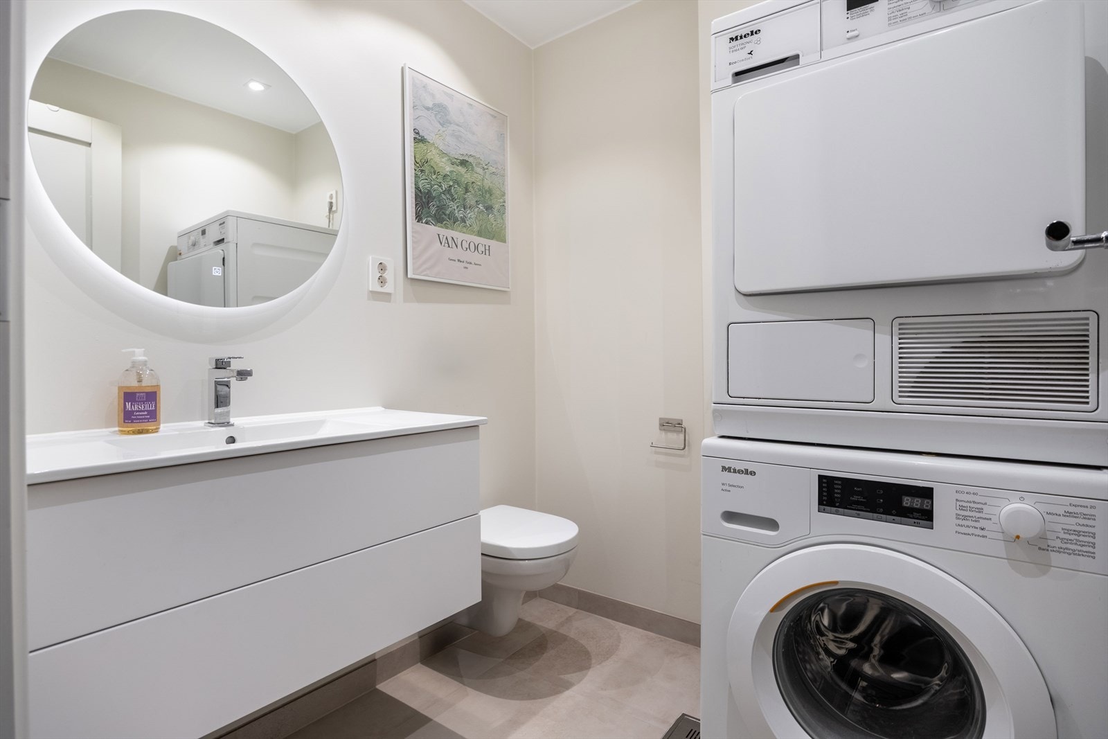 Vaskerom/bad pusset opp i 2025. Rommet har vegghengt wc, servant med skuffer, speil med lys og opplegg for vaskemaskin og tørketrommel. Galleribilde