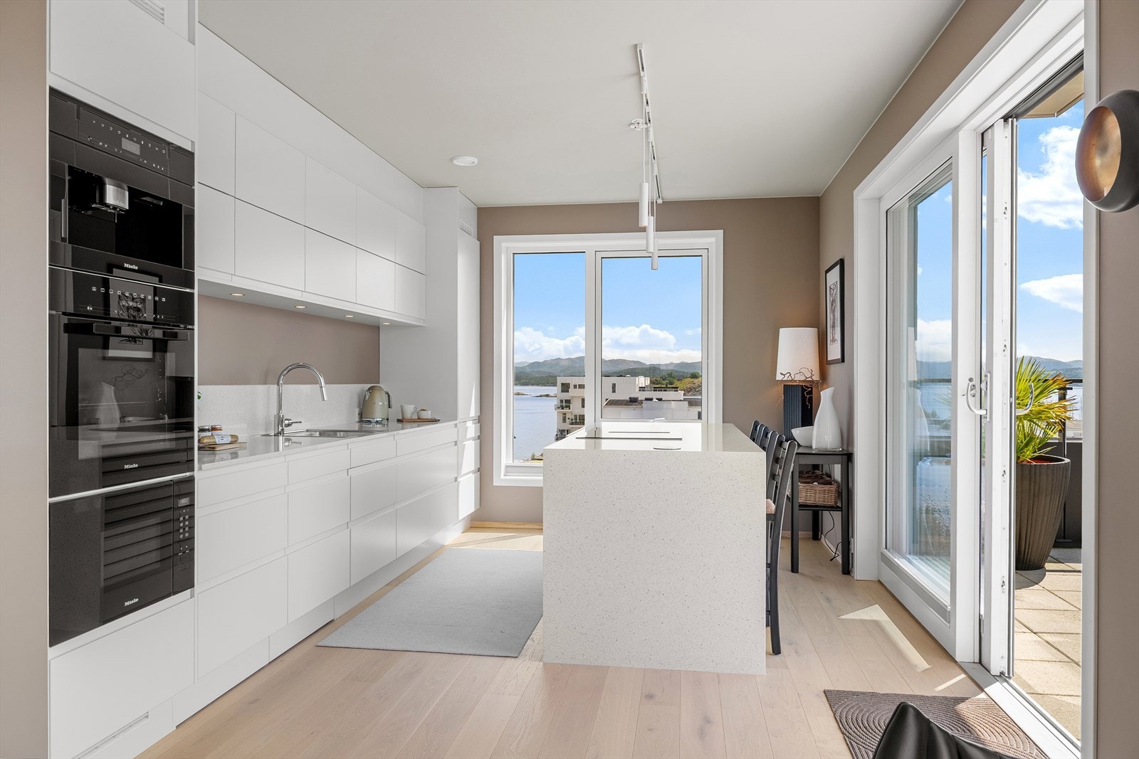 Kjøkken med hvite matte fronter og hvit benkeplate i stein. Kjøkkenet er levert av kvalitetsleverandøren Norema. Galleribilde