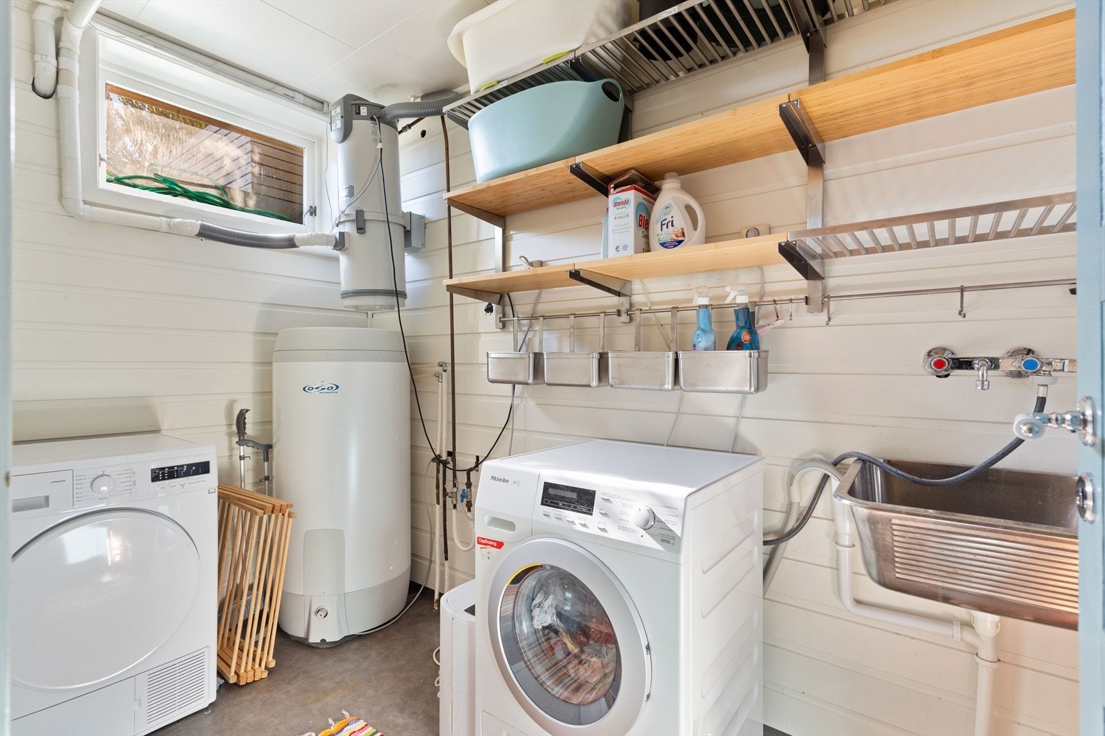 Vegg i vegg med toalettrommet er det etablert et eget vaskerom med utslagsvask, hyller og varmtvannsbereder. Galleribilde