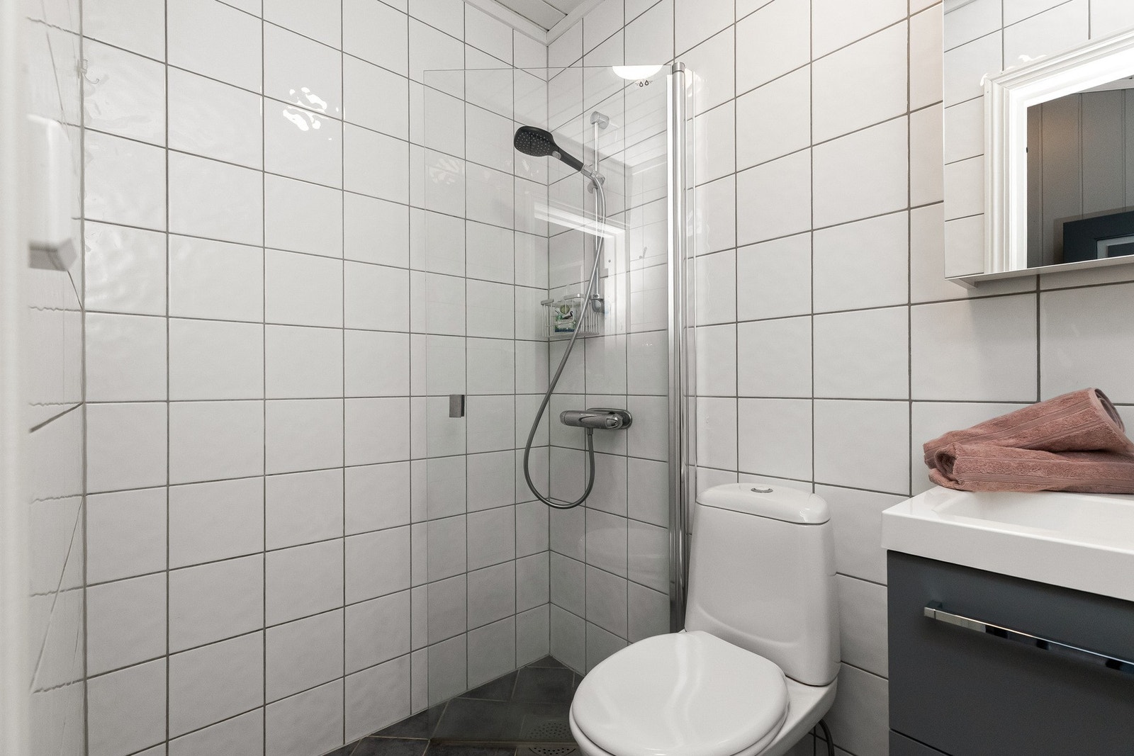 Badet inneholder servantskap med underskap, speilskap, dusjvegg og toalett. Galleribilde