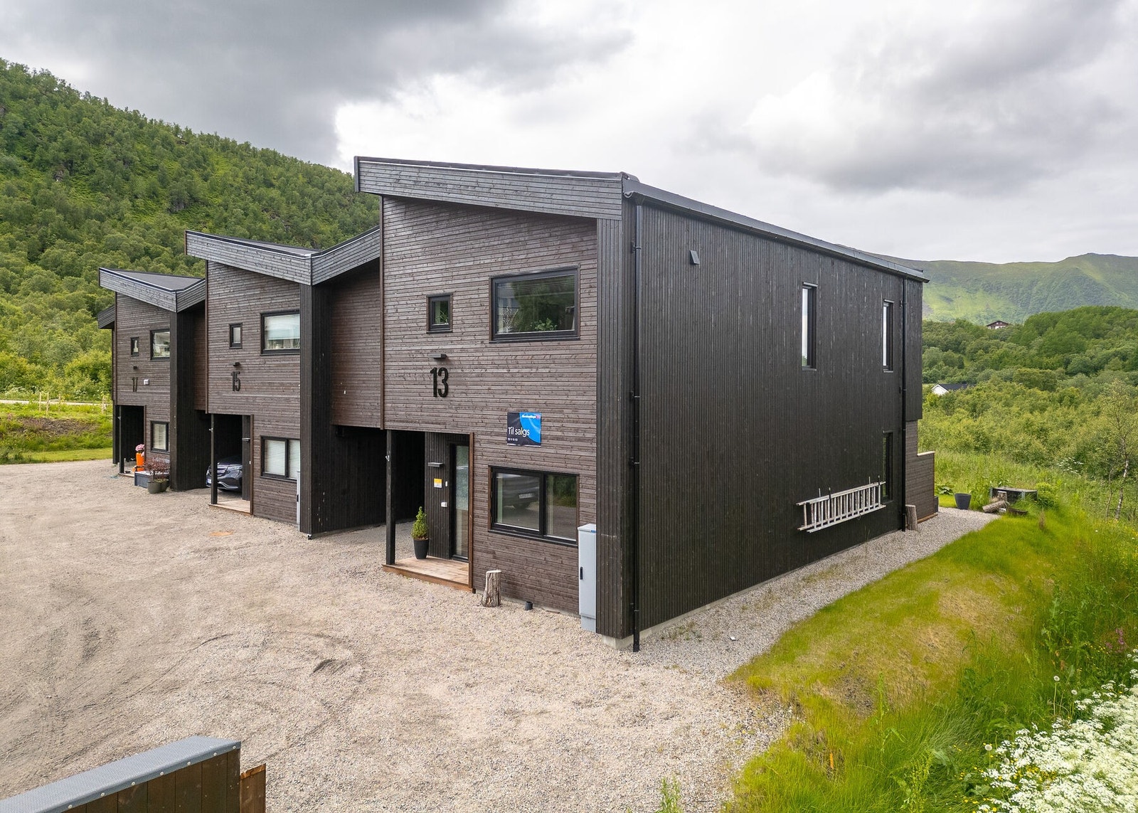 Fasade og uteområde. Tomten er opparbeidet med plen og beplantning. Galleribilde